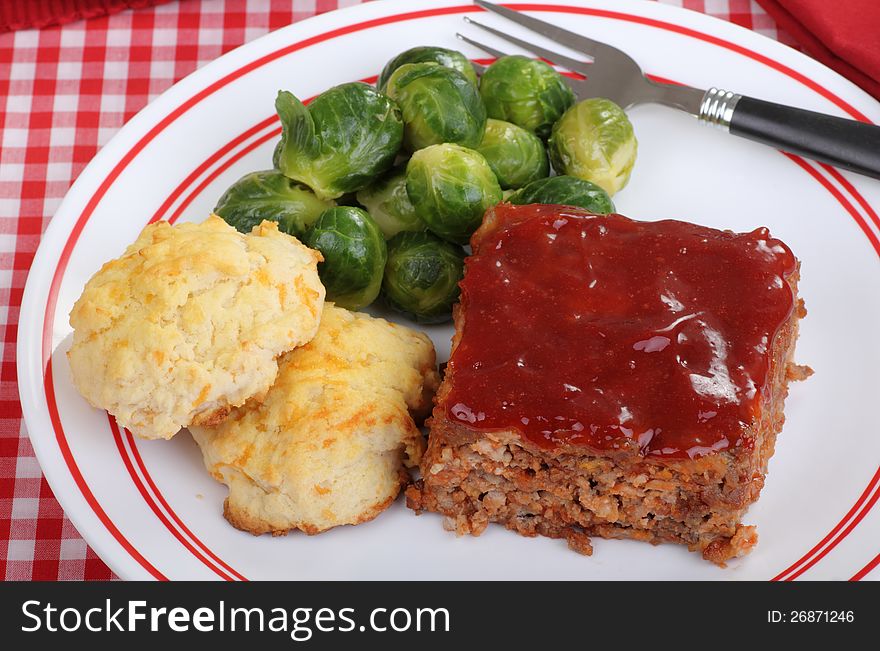 Top view of a meal of meatloaf, biscuits and brussels sprouts