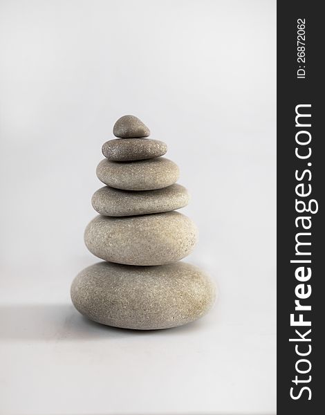 A zen tower arrangement of stones on white background. Symbol of inner peace, harmony and stability. A zen tower arrangement of stones on white background. Symbol of inner peace, harmony and stability.