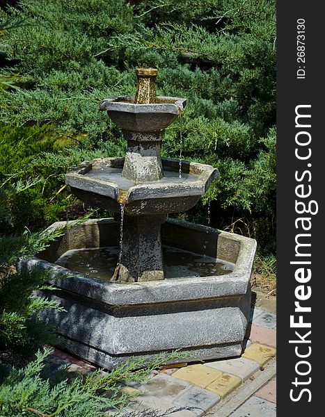 Fine stone fountain in park among trees