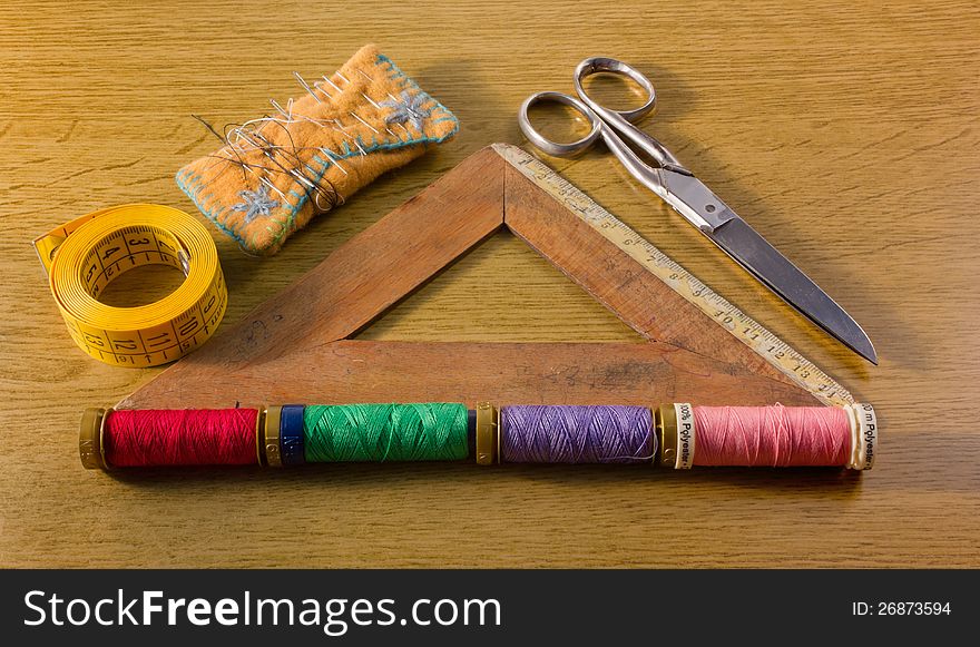 A few old sewing tools: pins, spools, scissors, tape and a wooden square ruler