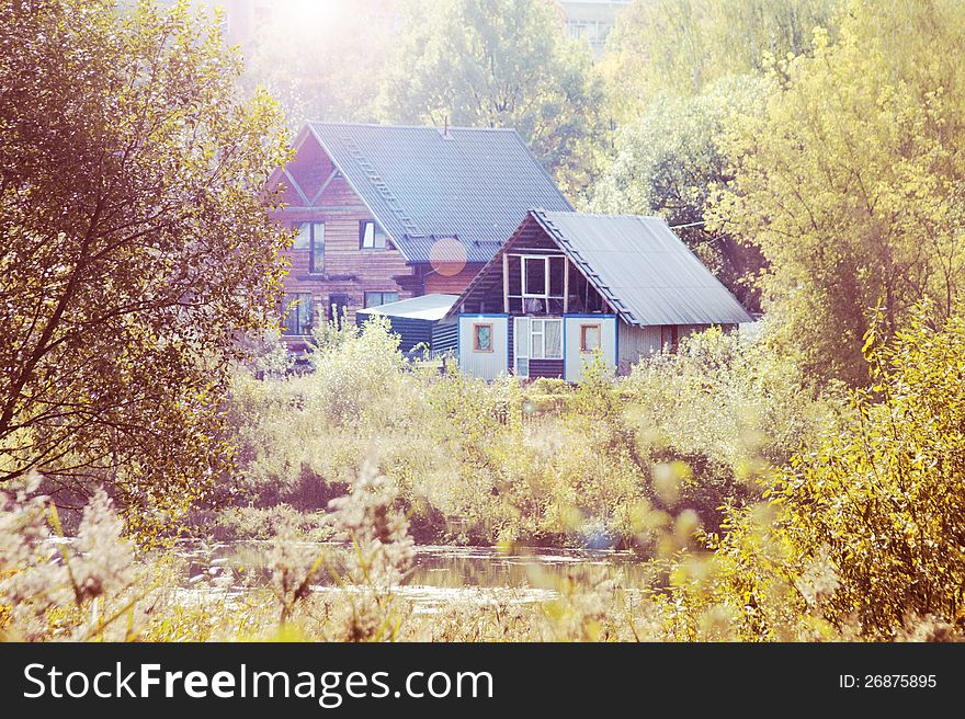 Two houses in the autumn forest on the bank of the river