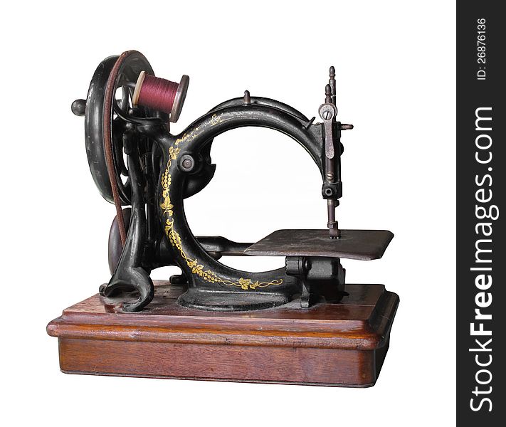 Old and worn black metal antique sewing machine turned by a hand crank, with a spool of red thread. Isolated on white. Old and worn black metal antique sewing machine turned by a hand crank, with a spool of red thread. Isolated on white.