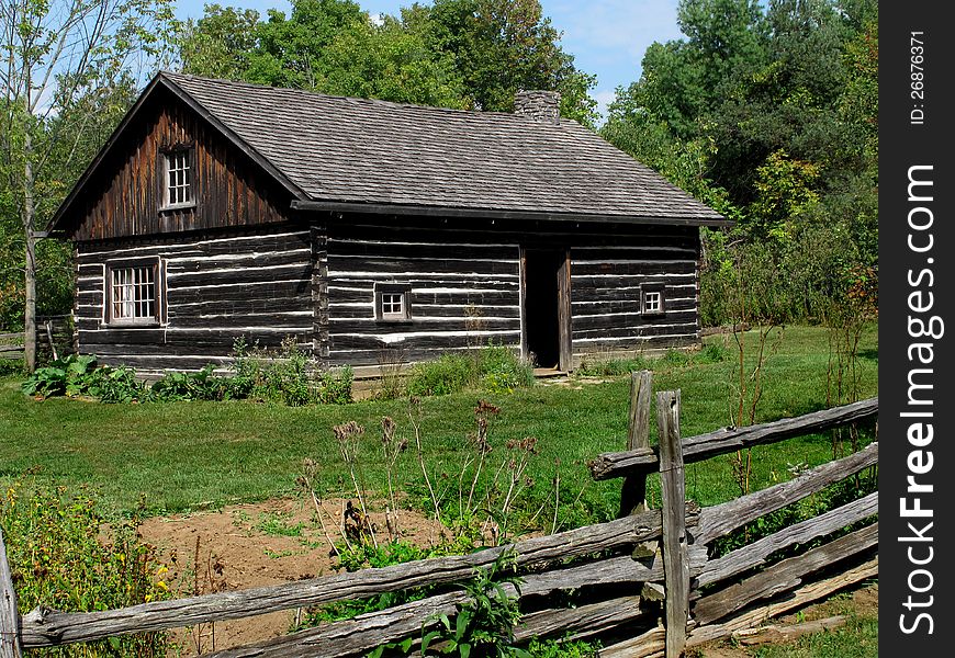 Old log house with yard and fence.