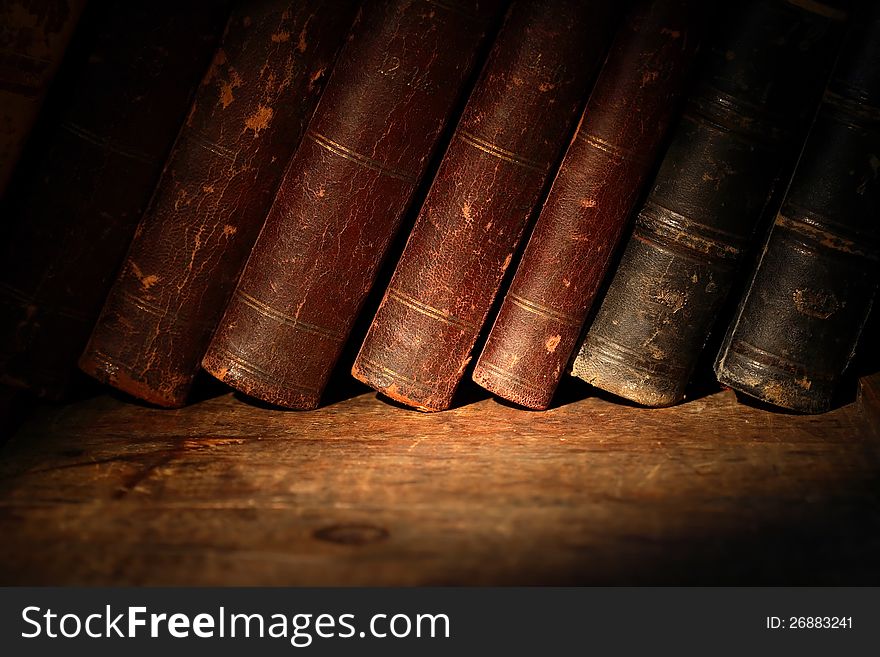 Stack of old books in a row on wooden surface