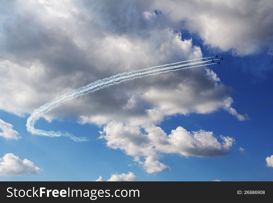 Four aircrafts living smoke trails in blue cloudy sky background