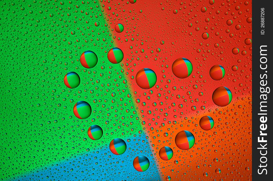 Drops of water on glass in a heart shaped. Colorful background is reflected in the drops. macro. Drops of water on glass in a heart shaped. Colorful background is reflected in the drops. macro