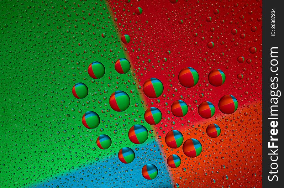 Drops of water on glass in a heart shaped. Colorful background is reflected in the drops. macro. Drops of water on glass in a heart shaped. Colorful background is reflected in the drops. macro