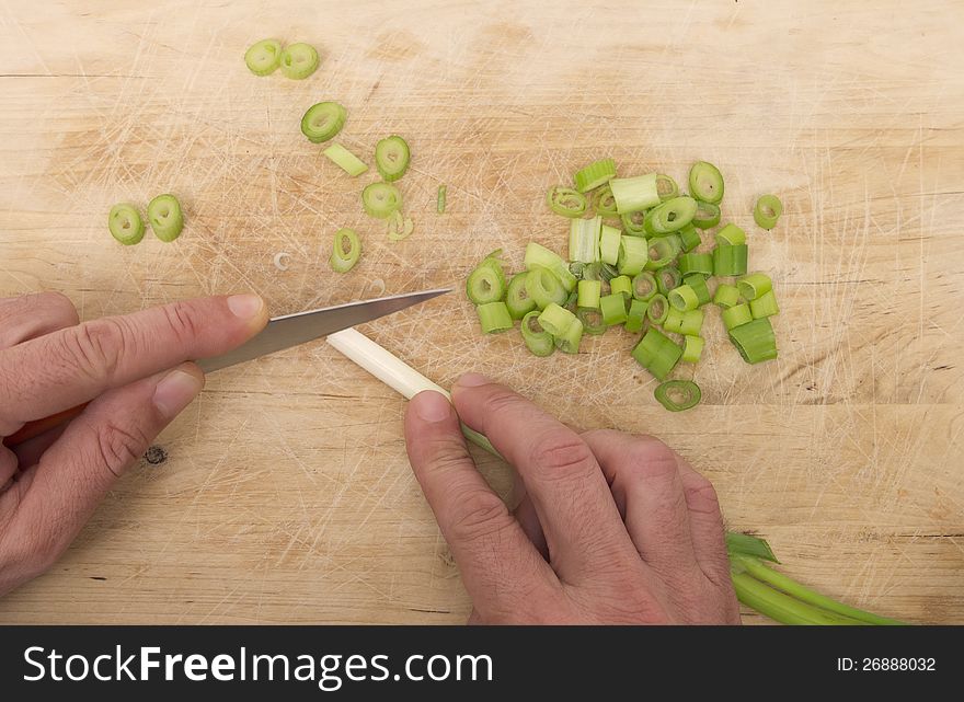 Two hands chopping green ognons on a wood surface. Two hands chopping green ognons on a wood surface