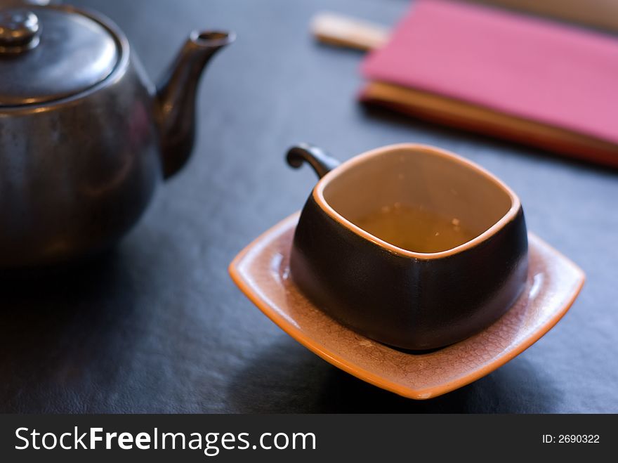 Teapot and teacup - focus on the front edge of the cup, shallow depth of field. Teapot and teacup - focus on the front edge of the cup, shallow depth of field.