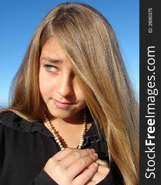 Head & Shoulders shot of a young girl on the beach, with pearls around her neck