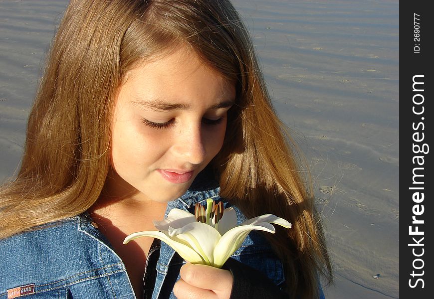 Young girl on the beach looking at a white flower. Young girl on the beach looking at a white flower