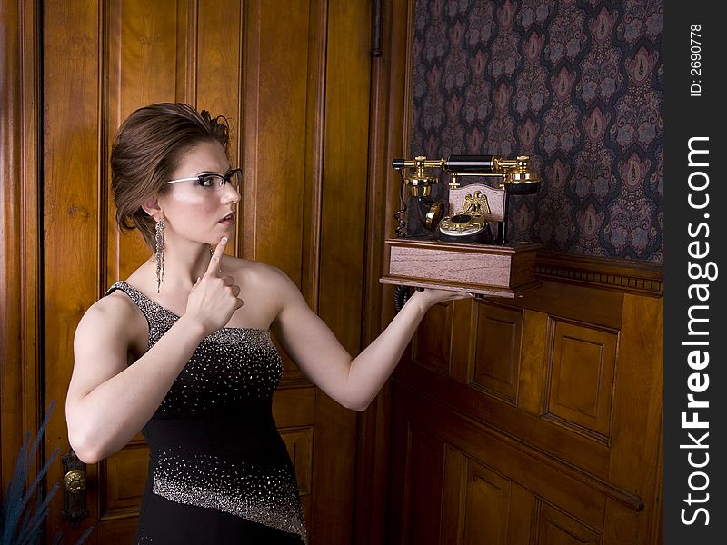 Beautiful young brunette woman wearing an evening gown looking perplexed at an old fashioned telephone. See my portfolio for more like this. Beautiful young brunette woman wearing an evening gown looking perplexed at an old fashioned telephone. See my portfolio for more like this.