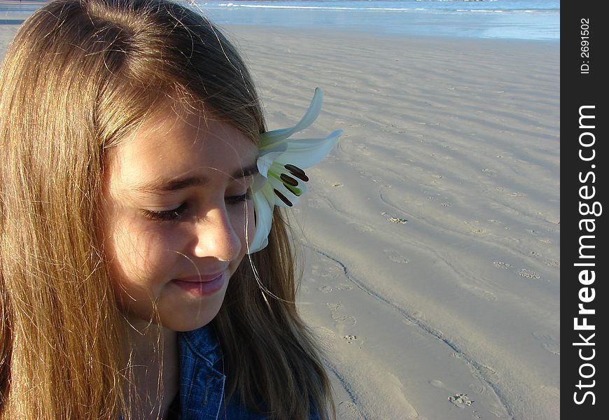 Young girl sitting on the beach with a flower in her hair. Young girl sitting on the beach with a flower in her hair