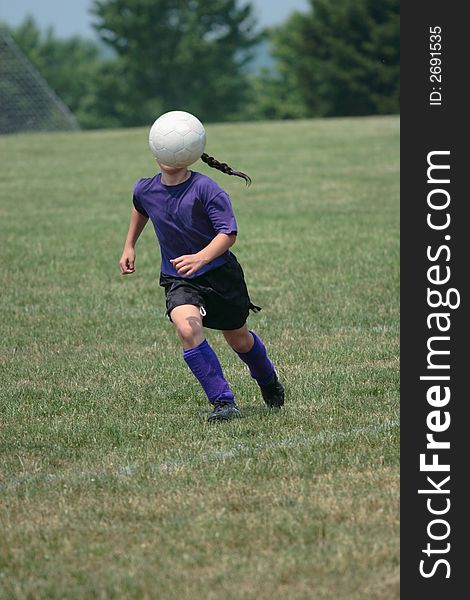 Girl kicking ball at soccer field during a game. Girl kicking ball at soccer field during a game.