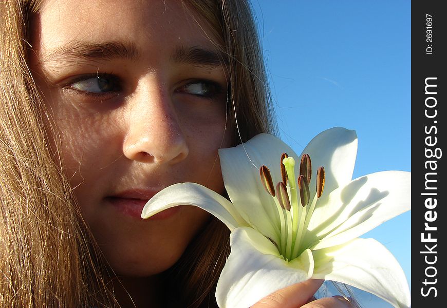 Young girl with a flower close to her face, Head & Shoulders Shot. Young girl with a flower close to her face, Head & Shoulders Shot