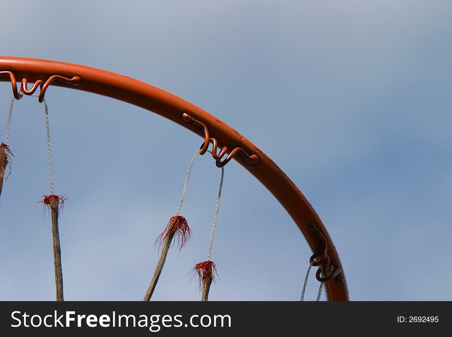 The ring of a basketball hoop. The net is very well worn and old. The ring of a basketball hoop. The net is very well worn and old.