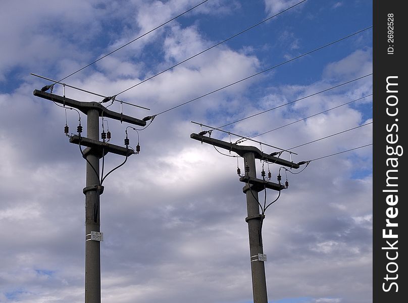 Electric pylons with the wires in front of blue sky with white clouds. Electric pylons with the wires in front of blue sky with white clouds