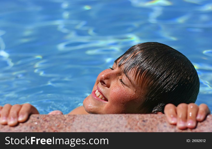 Young boy with eyes closed, smiling enjoying the sun in a swimming pool. Young boy with eyes closed, smiling enjoying the sun in a swimming pool