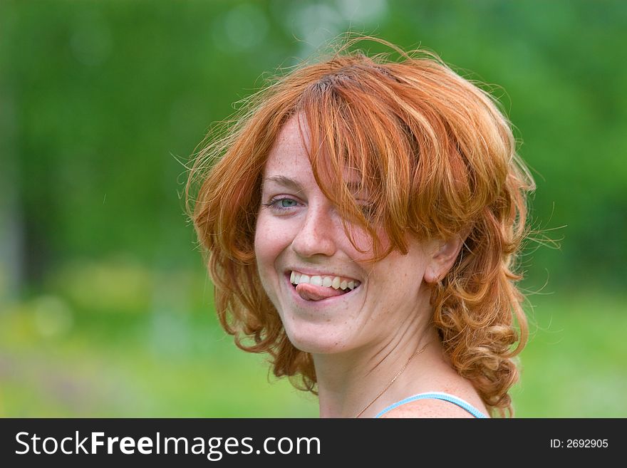 Outdoor shot of red-haired girl who put out tongue. Outdoor shot of red-haired girl who put out tongue