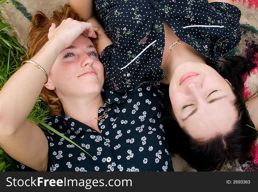 Girls lying on meadow, one of them are looking upward, one has eyes closed