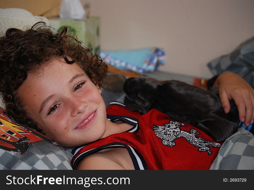 Boy happy to have his dog napping in his arms in his bed. Boy happy to have his dog napping in his arms in his bed