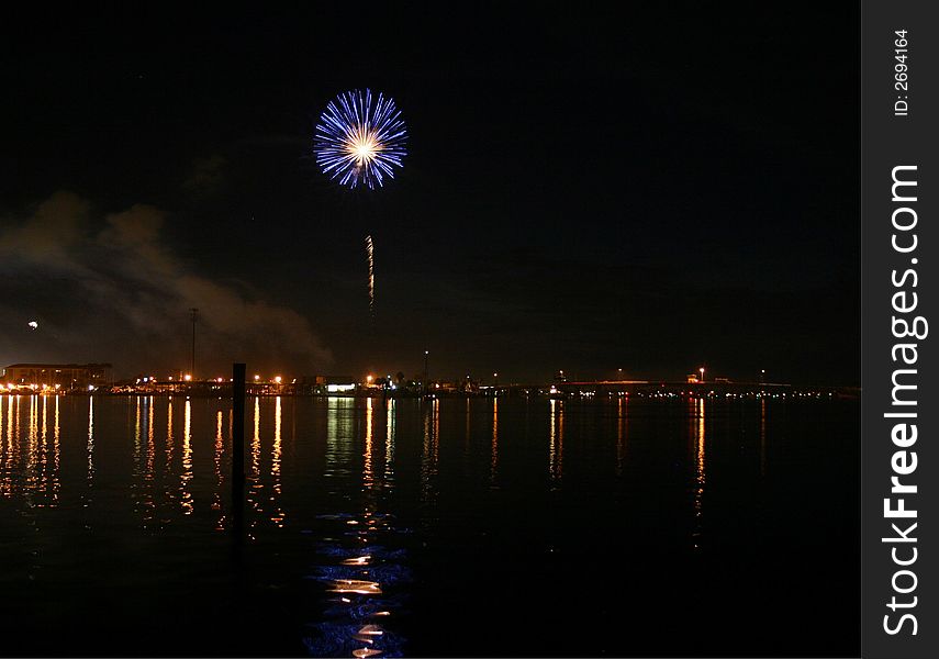 Blue firework exploding over ocean.