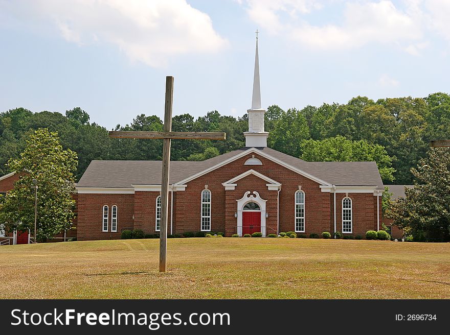 A church with a cross in the field out front. A church with a cross in the field out front