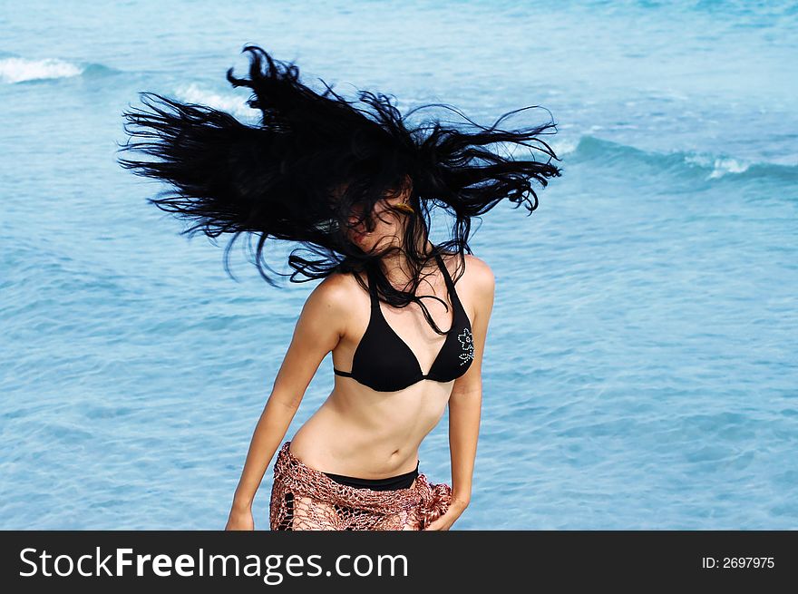 Bikini girl doing hairdance with ocean waves background. Bikini girl doing hairdance with ocean waves background