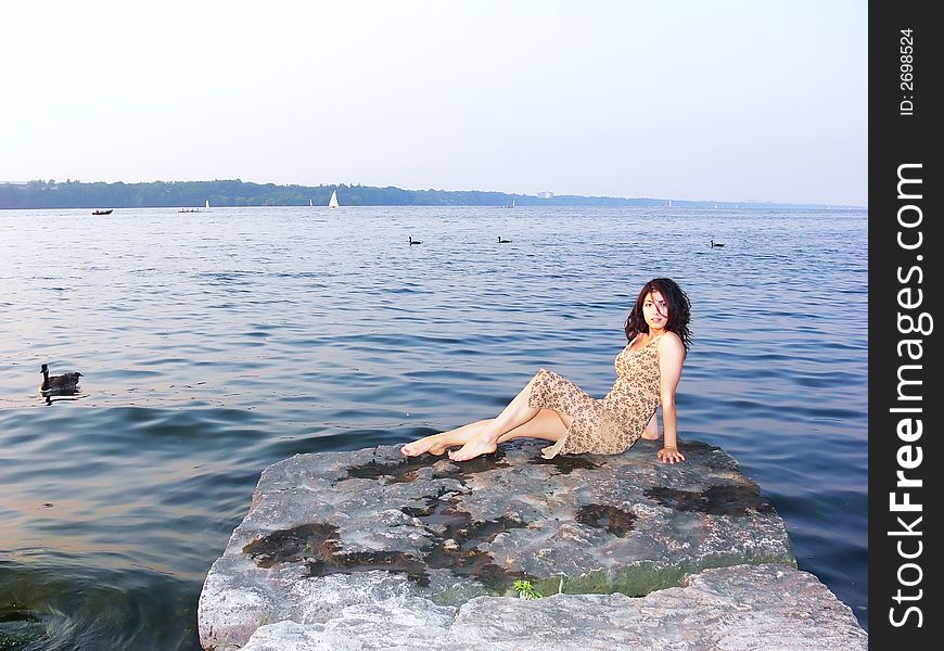 A young girl sitting on a big rock in the lake Ontario, resting and enjoying the
peace and quietness of the water. A young girl sitting on a big rock in the lake Ontario, resting and enjoying the
peace and quietness of the water.