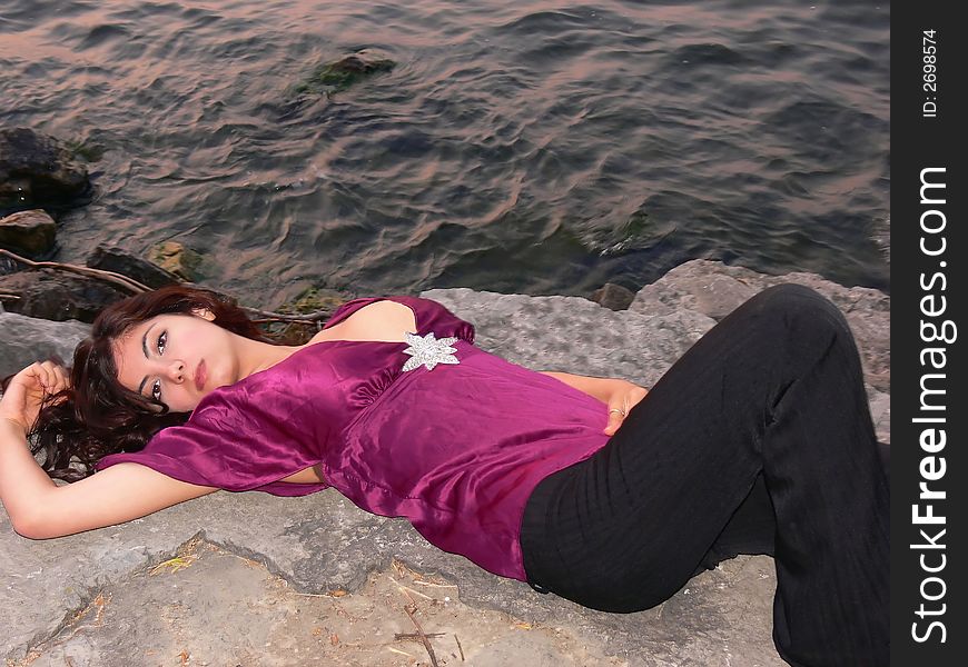 An lovely young lady laying on a big rock on the lake relaxing by sunset. An lovely young lady laying on a big rock on the lake relaxing by sunset.