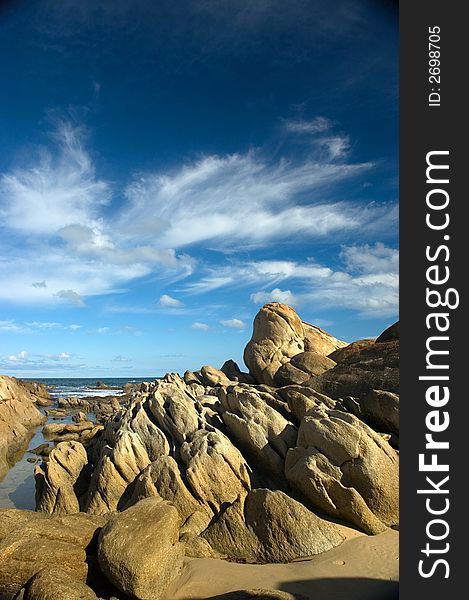 Rock outcrop on the coast with blue sky background. Rock outcrop on the coast with blue sky background
