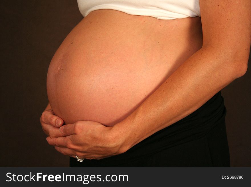 A woman tenderly holds her pregnant stomach. A woman tenderly holds her pregnant stomach.