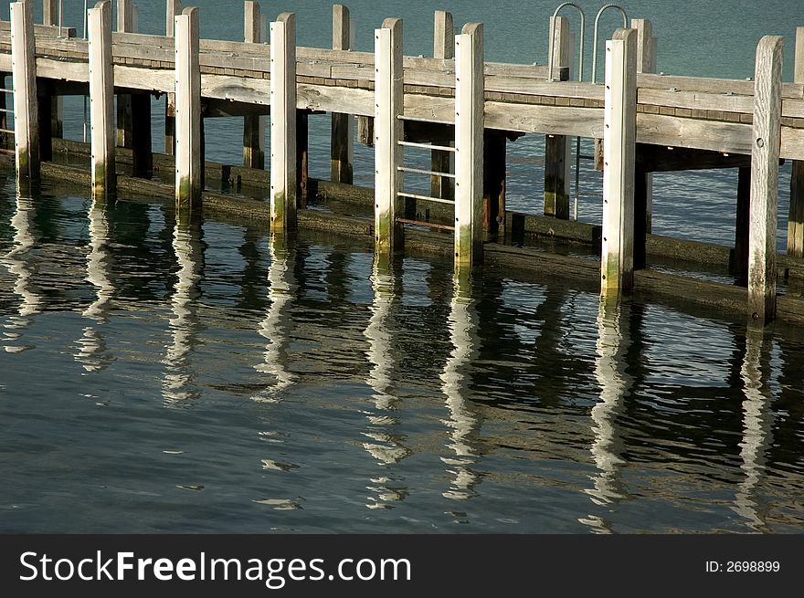 Wooden jetty reflected in calm harbour waters. Wooden jetty reflected in calm harbour waters