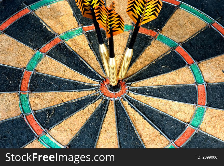 Three darts hitting the bullseye on a dart board