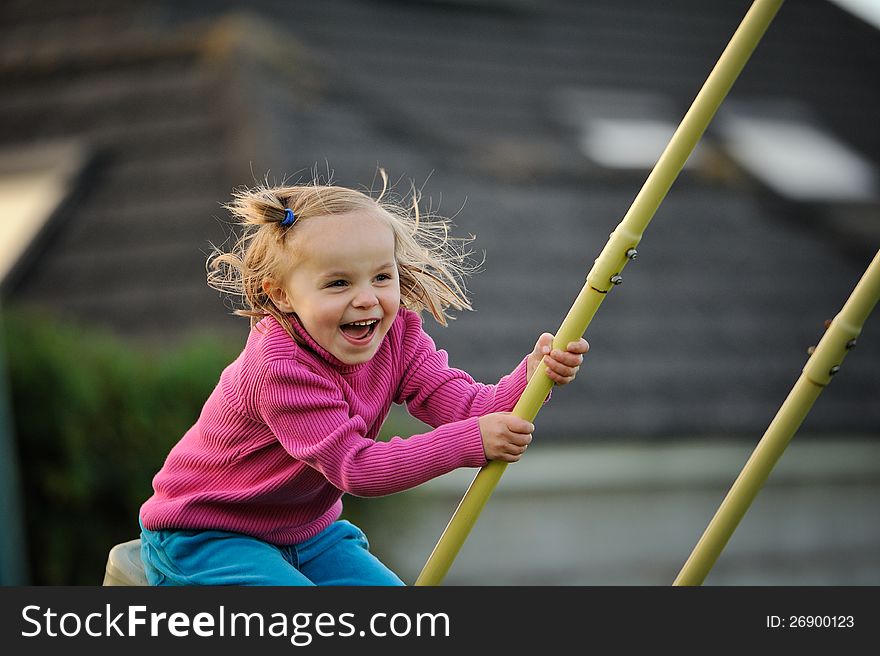 A young girl laughing on the swings. A young girl laughing on the swings.