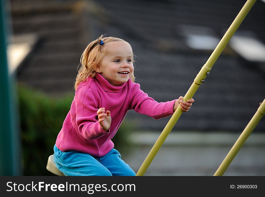 A happy child on swings, enjoying herself.