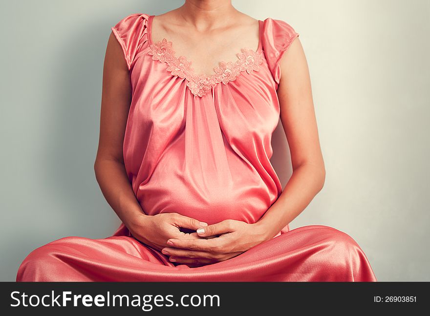 Pregnant woman doing yoga over light gray background