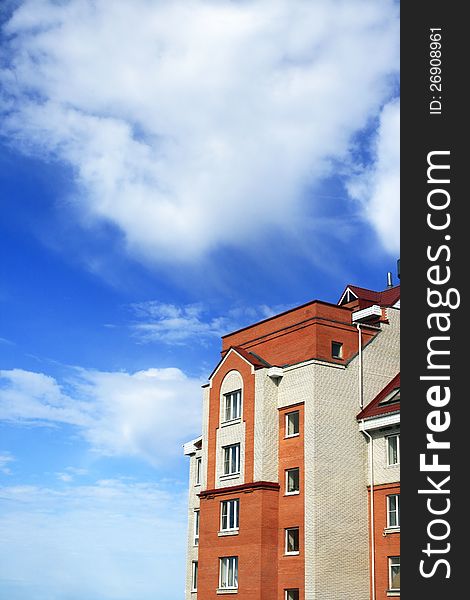 Photo of white-red brick house with red roof against beautiful sky. Photo of white-red brick house with red roof against beautiful sky