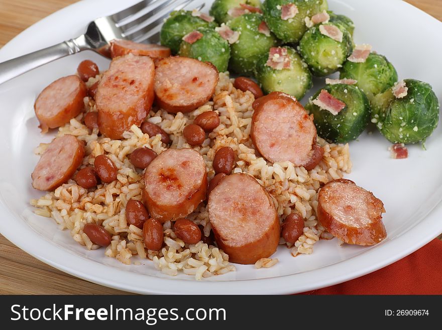 Sliced sausage and beans on rice with brussels sprouts. Sliced sausage and beans on rice with brussels sprouts