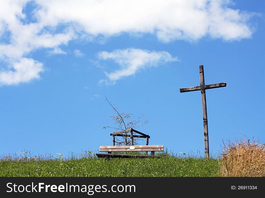 A cross and a wooden bank on a mountain in Bavaria. A cross and a wooden bank on a mountain in Bavaria