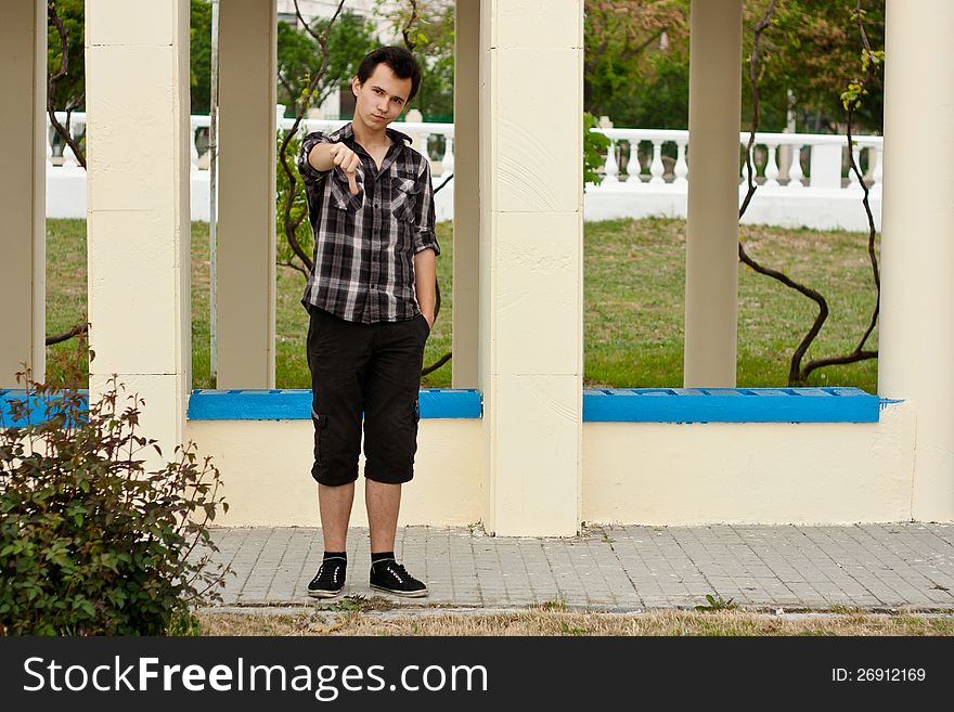Young man stay near the pillar and had show big finger down