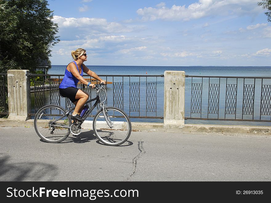A female cyclist bikes over a bridge with a water view. A female cyclist bikes over a bridge with a water view.