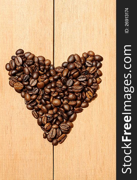 Heart shape coffee bean shot on the wooden background