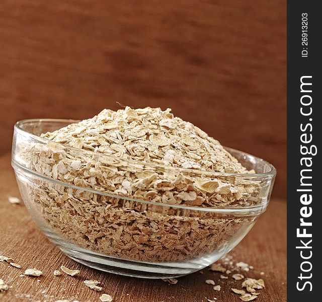 Oatmeal in glass bowl. Shot with wooden background