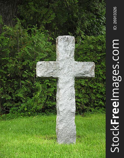 A stone cross stands against green foliage