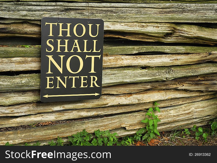A sign on a wall of wooden poles restricts entry. A sign on a wall of wooden poles restricts entry