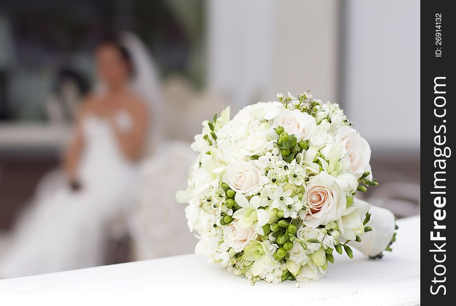Beautiful white wedding bouquet with bride sitting in the background - shallow dof