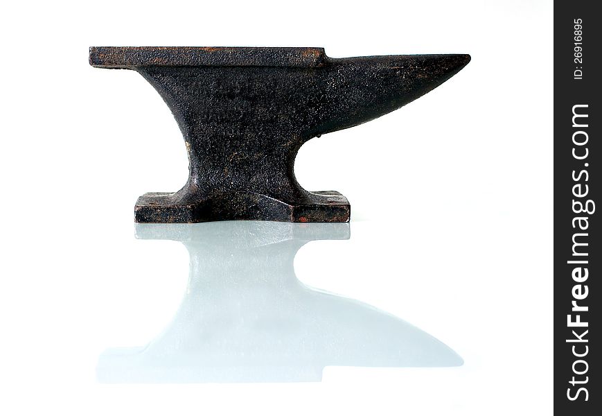 An old anvil on a glass plate with white background. An old anvil on a glass plate with white background