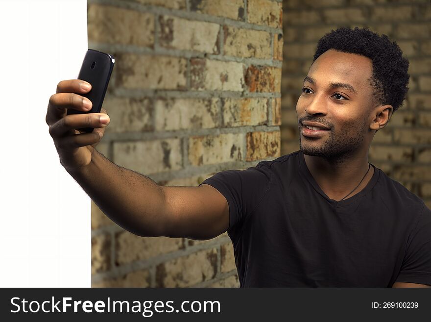 man taking selfie brick wall cellphone student holding smartphone social networking