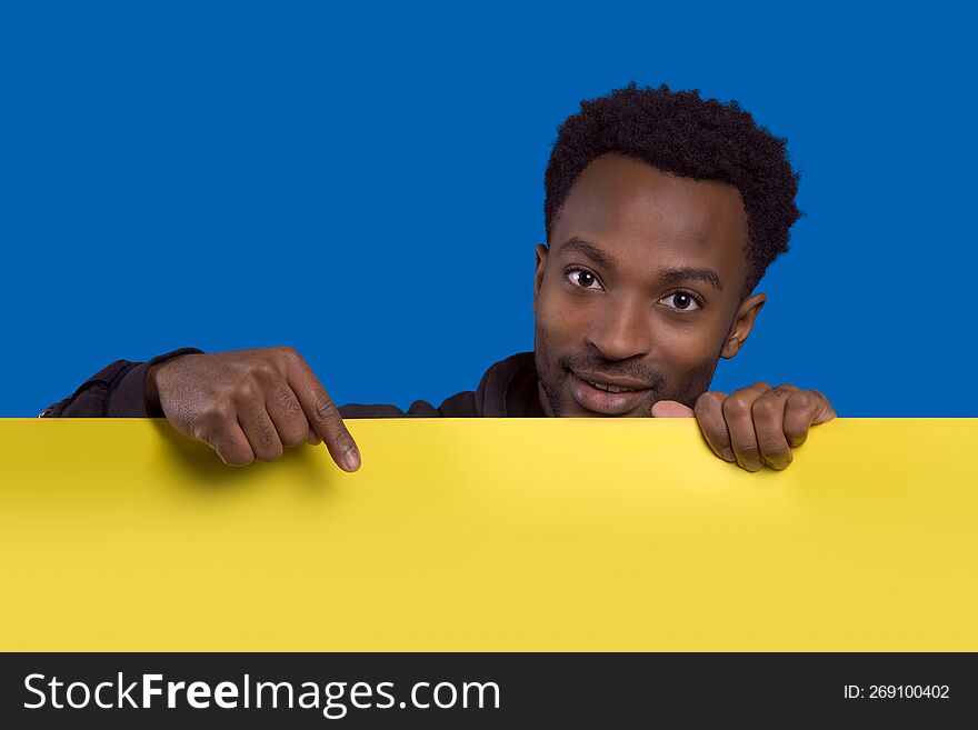 man holding and pointing board copy space background presentation banner poster yellow cardboard on blue background. man holding and pointing board copy space background presentation banner poster yellow cardboard on blue background